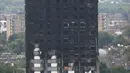 Kerusakan bangunan apartemen Grenfell Tower di London terlihat dari utara Kensington, Minggu (18/6). Gedung apartemen Grenfell Tower yang terbakar pada lepas tengah malam Rabu 14 Juni 2017 lalu dikhawatirkan roboh usai habis dilahap api. (TOLGA AKMEN/AFP)