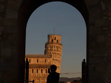 Turis mengambil gambar Menara Pisa di kota Pisa, Tuscany, Italia pada 28 November 2018. Kemiringan Menara Pisa yang tersohor kini telah stabil setelah sedikit diluruskan dalam upaya menyelamatkan situs pariwisata ternama dunia itu. (Tiziana FABI / AFP)