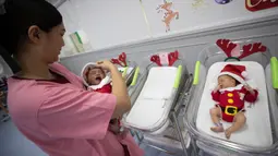 Perawat menggendong bayi yang baru lahir di Rumah Sakit Synphaet, Bangkok, Thailand, Selasa (24/12/2019). Bayi-bayi tersebut dipakaikan kostum sinterklas untuk menyambut Hari Raya Natal. (AP Photo/Sakchai Lalit)
