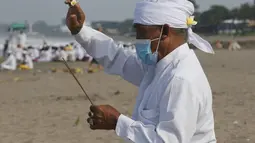 Seorang pria berdoa selama ritual Melasti di Bali, Senin (28/2/2022). Ritual yang dilakukan menjelang Hari Raya Nyepi umat Hindu ini diadakan untuk menyucikan alam semesta dari pengaruh buruk, perbuatan dan pikiran buruk. (AP Photo/Firdia Lisnawati)