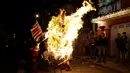  Sejumlah warga melihat pinata karakter Donald Trump yang dibakar saat perayaan tradisional, Pembakaran Iblis di Guatemala City, Guatemala (7/12). Perayaan Pembakaran Iblis ini digelar untuk mengusir roh-roh jahat. (Reuters/Luis Echeverria)