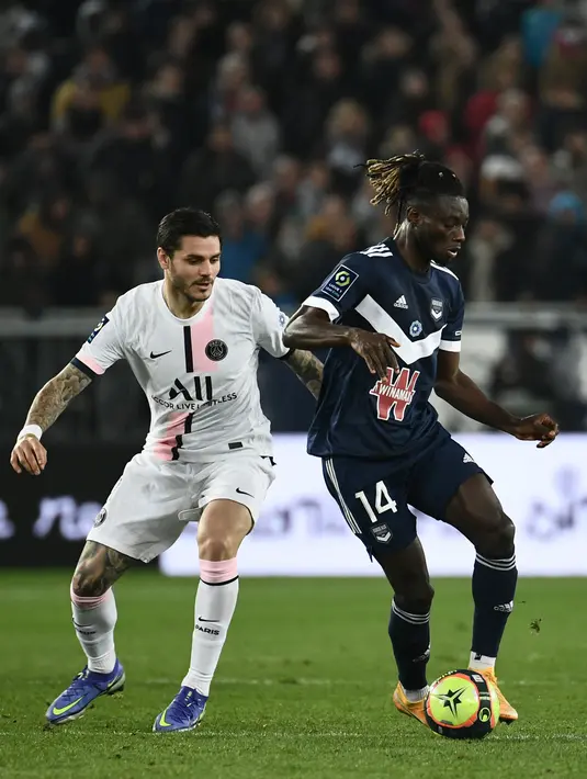 Penyerang Paris Saint-Germain (PSG) Mauro Icardi berebut bola melawan bek Bordeaux Gideon Mensah pada matchday ke-13 Liga Prancis 2021/2022 di Stadion Matmut Atlantique, Minggu (7/11/2021) dini hari WIB. PSG menang tipis 3-2, dengan dua gol disumbangkan Neymar. (Philippe LOPEZ/AFP)