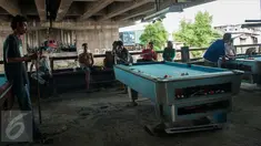 Sejumlah warga bermain biliar di kolong jembatan tol, Jakarta, Selasa (21/3). Tempat biliar sederhana ini menjadi tempat hiburan alternatif bagi masyarakat menengah kebawah di sekitar kolong tol. (Liputan6.com/Gempur M Surya)