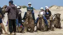 Turis bersiap untuk menunggang unta di sepanjang bukit pasir di Stockton Beach dekat Nelson Bay, Australia, Jumat (6/11/2020). Stockton Beach adalah rumah bagi bukit pasir bergerak terbesar di Belahan Bumi Selatan dengan beberapa di antaranya Tinggi 30 meter (98 kaki). (AP Photo/Mark Baker)