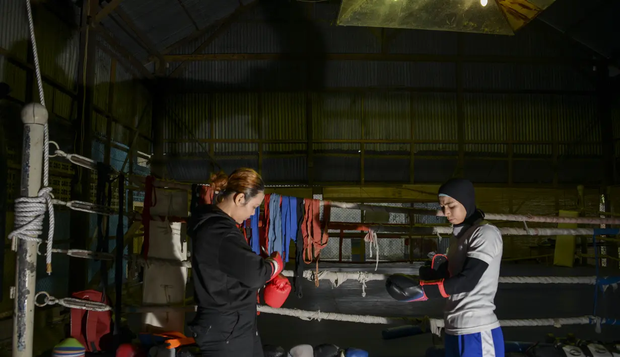 Petinju amatir wanita memakai sarung tinju sebelum mengikuti sesi latihan di sebuah pusat olahraga di Banda Aceh (24/8/2020). (AFP Photo/Chaideer Mahyuddin)