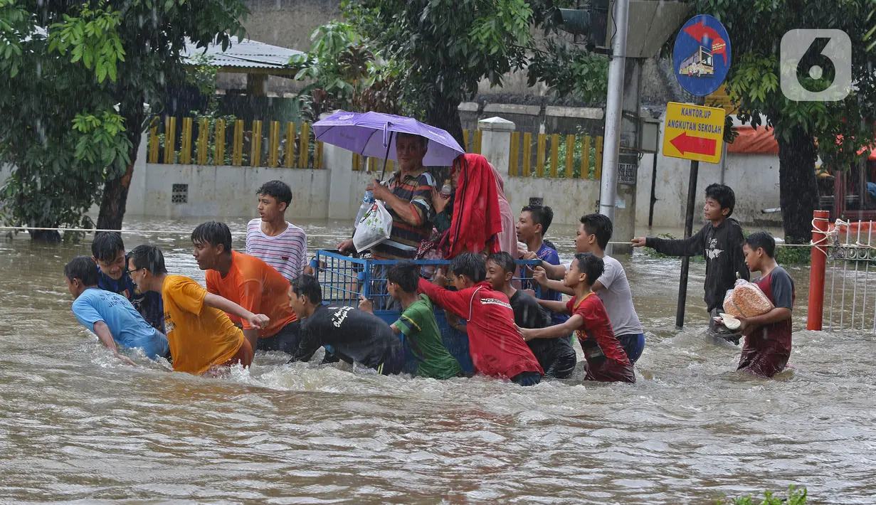 Warga menggunakan jasa gerobak untuk menghindar banjir yang merendam Jalan Pondok Raya Gede, Jakarta Timur, Selasa (25/2/2020).  Sejumlah ruas jalan tergenang dan akses ke beberapa wilayah terputus, salah satunya Jalan Pondok Raya Gede. (Liputan6.com/Herman Zakharia)
