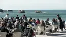 Warga dan turis menikmati minuman di sebuah kafe selama cuaca musim dingin yang hangat di sepanjang garis pantai kota Biarritz di Perancis barat (17/2). Kota ini terletak di region Aquitane, Departemen Pyrénées-Atlantiques. (AFP Photo/Iroz Gaizka)