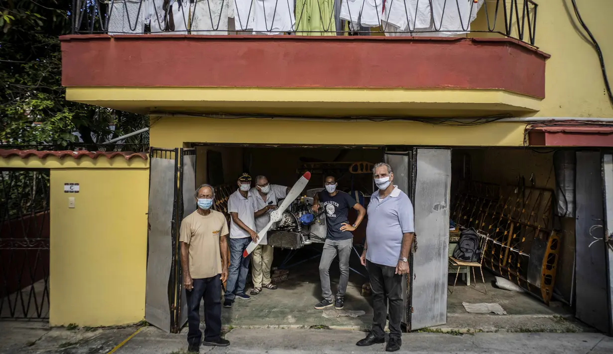 Adolfo Rivera (kiri) bersama mereka yang membantunya membuat pesawat terbang kayu, dua tempat duduk, berfoto dengan Presiden Cuba Aviation Club René González (kanan) di garasi gedung apartemennya Havana, Kuba, 19 Februari 2021. (AP Photo/Ramon Espinosa)
