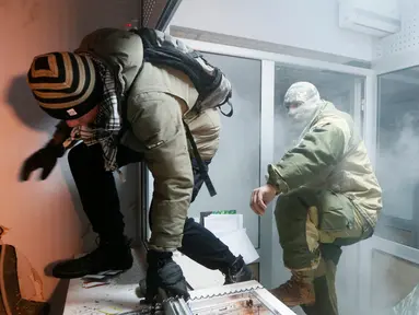 Dua orang demonstran saat merusak seisi bank Rusia, Sberbank di Kiev, Ukraina (21/11). Aksi dilakukan untuk memperingati tragedi kerusuhan 2014 yang menyebabkan lebih dari 100 warga Ukraina tewas. (REUTERS/Valentyn Ogirenko)