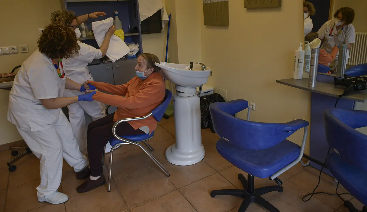 Maribel Elizondo, 90 tahun, dibantu oleh penata rambut Gloria Cerdan dan pekerja kesehatan di salon rambut di panti jompo Ibaneta, di desa kecil Erro, Spanyol utara, Senin (22/3/2021). Setiap minggu, pada hari Senin, Gloria Cerdan melayani penghuni panti jompo. (AP Photo/Alvaro Barrientos)