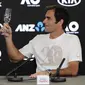 Juara Australia Terbuka 2018 Roger Federer mengajak bersulang pada konferensi pers usai mengalahkan Marin Cilic di final, Minggu (28/1/2018). (AP Photo/Vincent Thian)