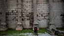 Seorang perempuan dengan masker berjalan di situs kuno Perpustakaan Hadrian di distrik Monastiraki, pusat kota Athena, Rabu (29/12/2021). Organisasi Kesehatan Dunia (WHO) memperingatkan lonjakan kasus Covid-19 varian Omicron dapat menyebabkan fasilitas kesehatan kewalahan. (Angelos Tzortzinis/AFP)
