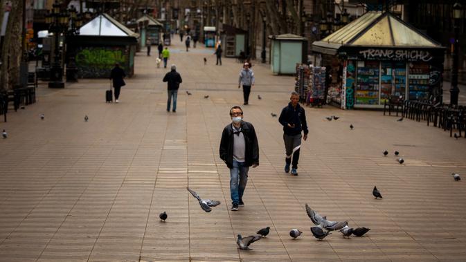 Warga berjalan di sepanjang La Ramblas, Barcelona, Spanyol, Minggu (15/3/2020). Pemerintah Spanyol memberlakukan lockdown setelah negara berpenduduk 47 juta jiwa itu terdampak virus corona COVID-19 paling parah kedua di Eropa setelah Italia. (AP Photo/Emilio Morenatti)