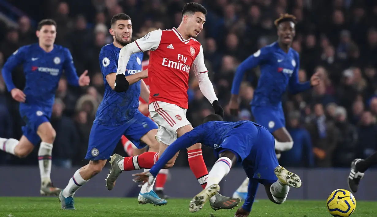 Striker Arsenal, Gabriel Martinelli, berebut bola dengan pemain Chelsea pada laga Premier League pekan ke-24 di Stamford Bridge, London, Rabu (22/1). Arsenal tahan imbang Chelsea 2-2. (AFP/Daniel Leal-Olivas)