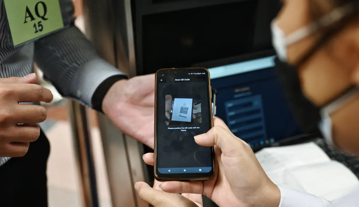 Petugas menggunakan kode QR untuk memasuki jalur masuk baru di Bandara Internasional Suvarnabhumi saat berlatih prosedur untuk pembukaan kembali Thailand, di Bangkok, Rabu (27/10/2021). Mulai 1 November, Thailand dibuka kembali tanpa karantina untuk yang divaksinasi penuh. (Lillian SUWANRUMPHA/AFP)