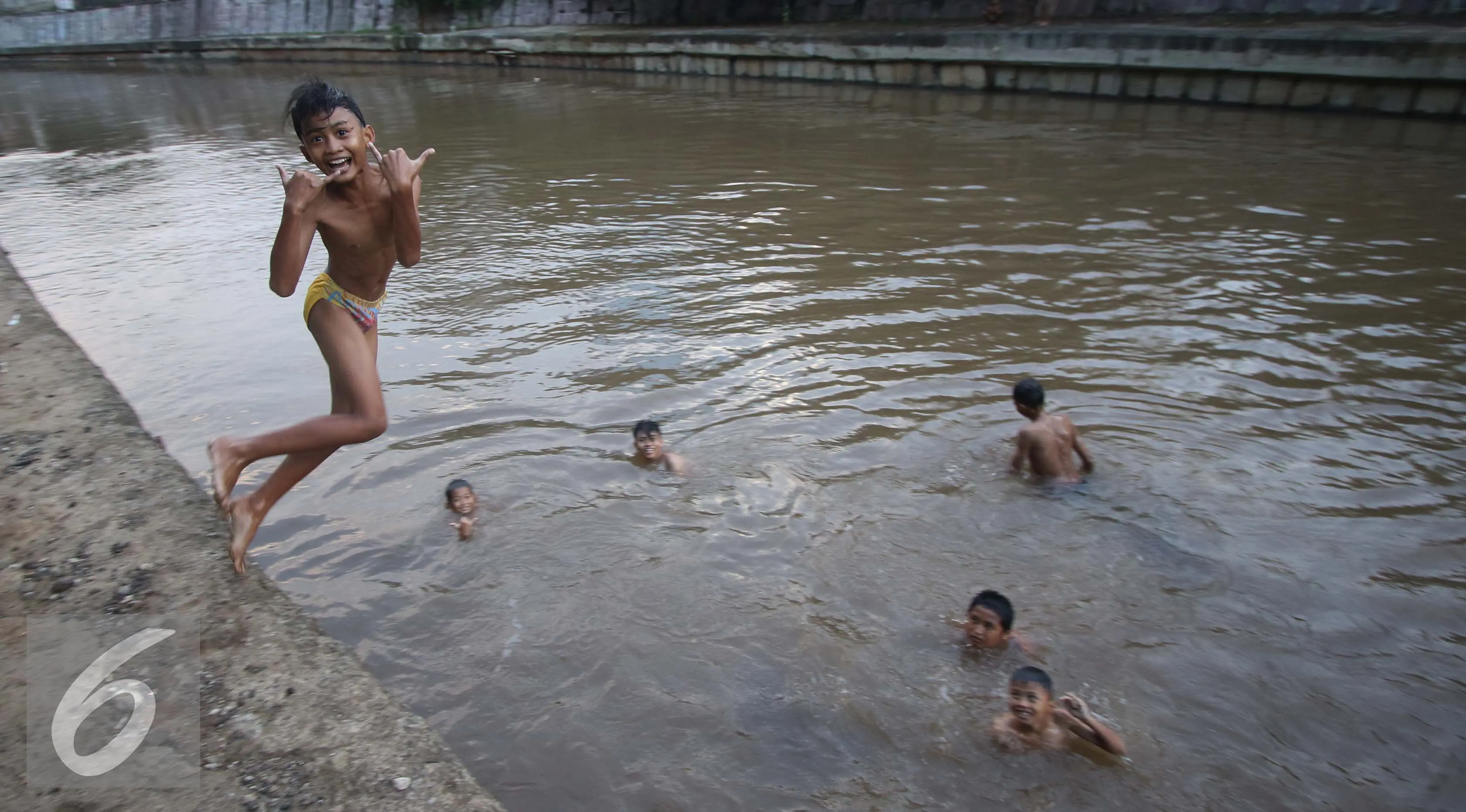 Sejumlah anak berumur belasan tahun riang gembira mandi di sungai Ciliwung, Jakarta, Rabu (16/11). Air di Sungai Ciliwung yang mulai bersih menjadi daya tarik anak-anak ini untuk mandi di sana. (Liputan6.com/Gempur M Surya)