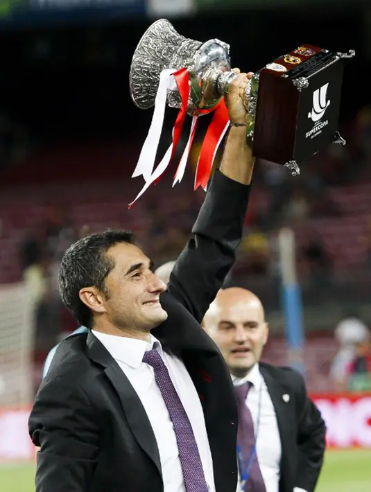 Pelatih Athletic Bilbao, Ernesto Valverde mengangkat trofi usai menang agregat atas Barcelona di leg kedua Piala Super Spanyol di stadion Camp Nou, Barcelona, Spanyol, (18/8/2015).  Athletic Bilbao menang dengan agregat akhir 1-5. (AFP/QUIQUE GARCIA)