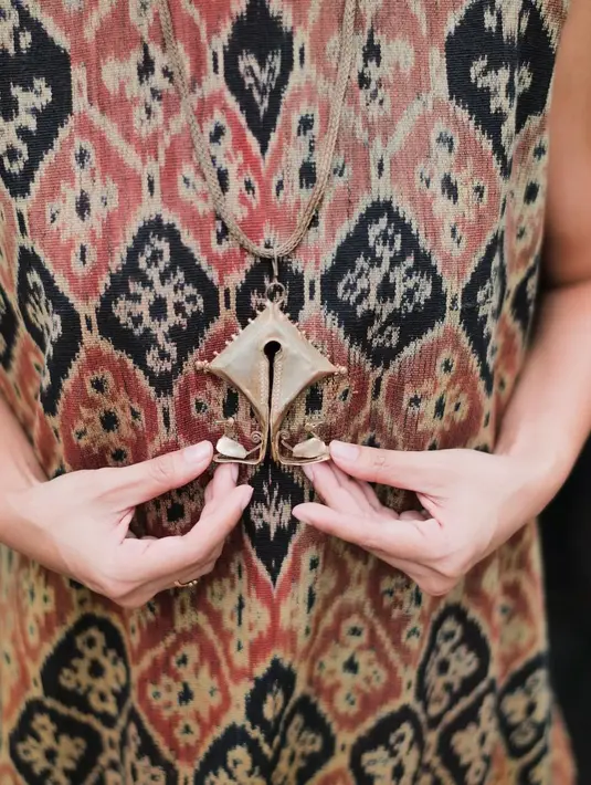 Andien tampil memesona dengan gaun panjang hitam polos tanpa lengan yang mengembang di bagian bawah. Gaun ini dilapisi kain tenun bermotif belah ketupat selang-seling merah bata dan hitam. Motifnya keemasan. Penampilan pemilik album Bisikan Hati disempurnakan dengan dua kalung beda ukuran dan ketebalan plus sepasang anting. Rambutnya dicepol. Riasan natural. (Foto: Dok. Instagram @andienaisyah)