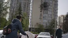 Orang-orang melewati sebuah gedung apartemen yang rusak akibat drone yang ditembak jatuh, selama serangan semalam Rusia, di Kyiv, Ukraina, Senin, 8 Mei 2023. (AP Photo/Andrew Kravchenko)