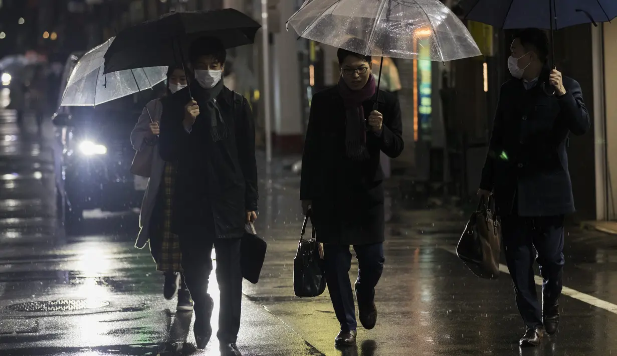 Orang-orang berjalan menuju stasiun kereta api, melewati restoran dan bar, banyak di antaranya ditutup dalam keadaan darurat, di Tokyo (5/3/2021). Data statistik mencatat Jepang hingga saat ini memiliki 435.548 kasus dengan 8.052 kematian akibat Covid-19. (AP Photo/Hiro Komae)
