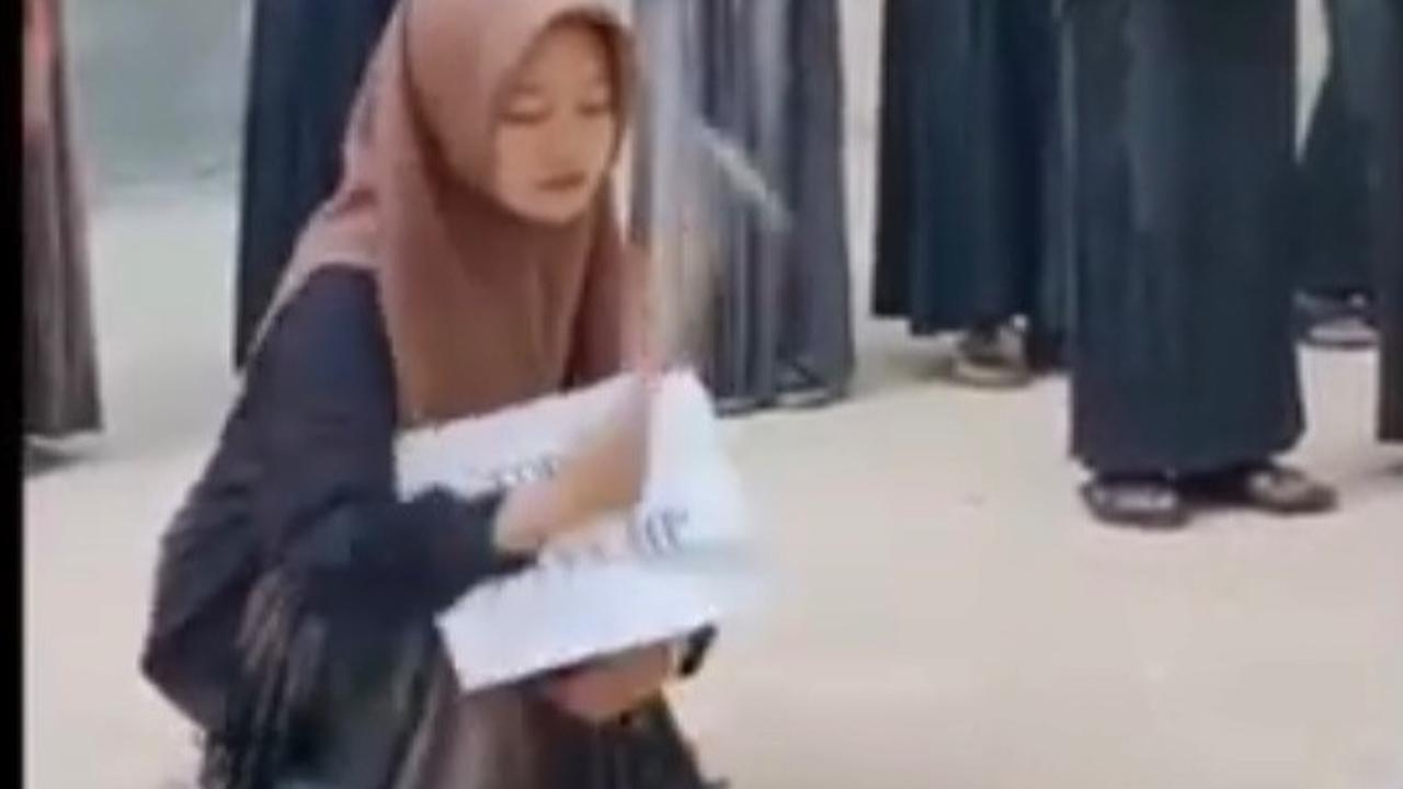 Sebagai hukuman, santriwati ini harus menghancurkan hpnya sendiri. <br><br>Berjongkok, santriwati ini terlihat membawa palu untuk menghancurkan hp miliknya.