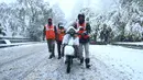 Pekerja mendorong skuter melintasi jalan yang tertutup salju di kota utama Kashmir, Srinagar, Kamis (7/11/2019). Srinagar menyambut salju pertama musim ini yang mulai turun. (Photo by Tauseef MUSTAFA / AFP)