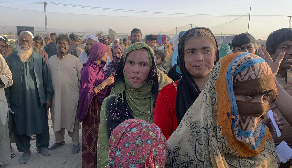 Keluarga Afghanistan berkumpul untuk menerima bahan makanan yang didistribusikan oleh organisasi Kristen yang berbasis di Islamabad di pinggiran Chaman, sebuah kota perbatasan di provinsi Baluchistan barat daya Pakistan, Selasa (31/8/2021). (AP Photo)