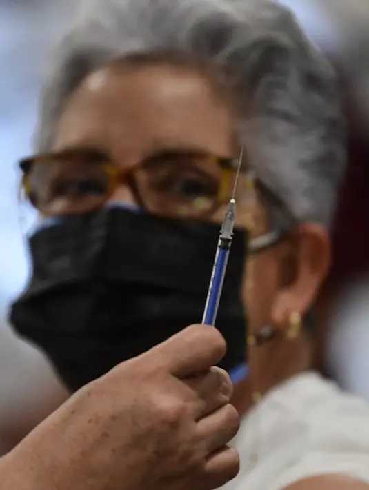 Perawat bersiap menyuntikkan dosis ketiga vaksin COVID-19 AstraZeneca di Centro de Estudios Superiores Navales (CENCIS) di Mexico City, Selasa (7/12/2021). Ibu kota Meksiko pada hari Selasa mulai memberikan vaksinasi booster untuk orang yang berusia di atas 60 tahun. (Pedro PARDO/AFP)