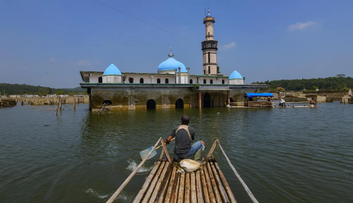 Warga menggunakan perahu  menyaksikan puing-puing bangunan mesjid dan rumah yang kembali muncul di kawasan Bendungan Karian yang mengering di Kampung Somang, Lebak, Banten, Jumat, 7 Agustus 2026. (KLY/ Arie Basuki)
