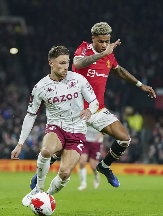 Penyerang Manchester United, Marcus Rashford berusaha merebut bola dari gelandang Aston Villa, Matty Cash pada pertandingan putaran ketiga Piala FA di stadion Old Trafford di Manchester, Inggris, Selasa (11/1/2022). MU menang atas Aston Villa 1-0. (AP Photo/Jon Super)