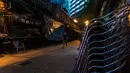 Seorang pria mengenakan masker pelindung melintas di jalanan sepi di kawasan hiburan malam Lan Kwai Fong, Hong Kong (5/5/2020). Kebijakan pemerintah Hong Kong itu membuat gemerlap hiburan malam di Lan Kwai Fong meredup seketika. (AFP/May James)