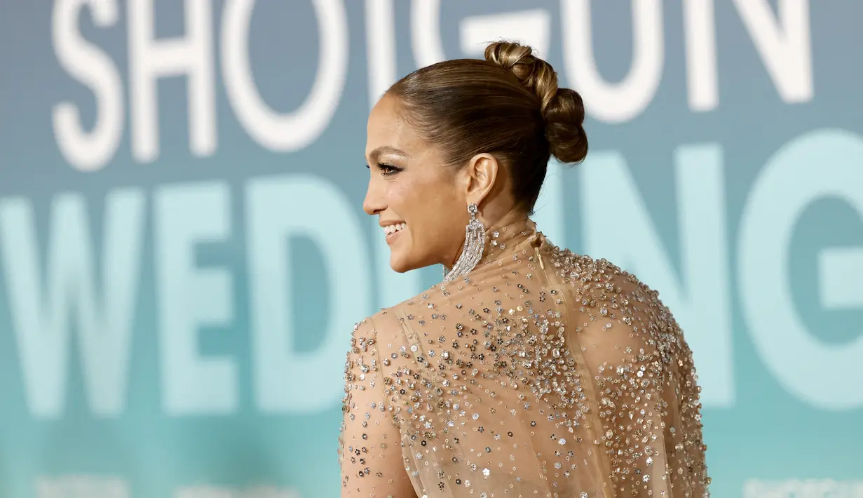 Aktris Jennifer Lopez berpose di pemutaran perdana film "Shotgun Wedding" di Los Angeles di TCL Chinese Theater di Hollywood, California (18/1/2023). Lapisan smoky eye shadow yang berani menambah kesan dramatis, sedangkan kilau segar dari lip gloss menambahkan sentuhan feminin. Dia mengguncang anting-anting perak yang menjuntai di atas bahunya dan membawa kopling velour kuning berbentuk kotak. (Emma McIntyre/Getty Images/AFP)
