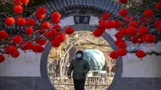 Seorang pria yang mengenakan masker berjalan melewati pepohonan yang dihiasi lentera untuk Tahun Baru Imlek di sebuah taman umum di Beijing, Jumat, 20 Januari 2023. Tahun Kelinci secara resmi dimulai pada 22 Januari. (AP Photo/Mark Schiefelbein)