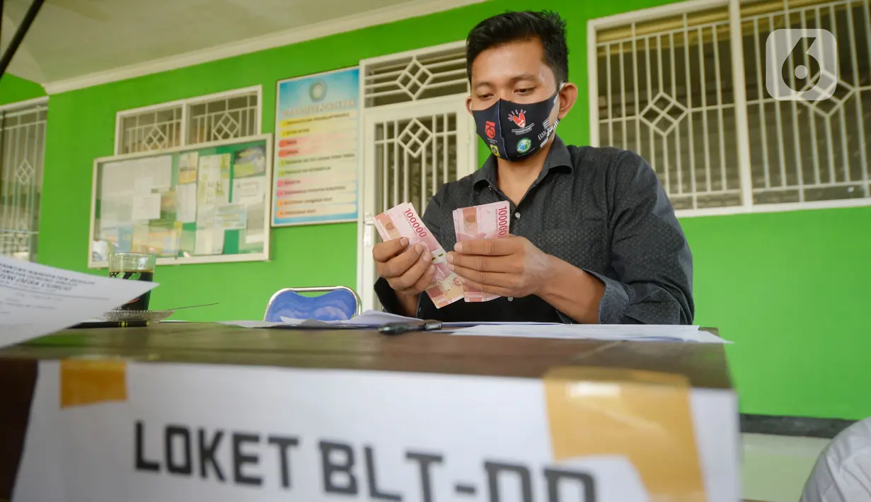 Petugas sedang menyerahkan Bantuan Langsung Tunai Dana Desa (BLT-DD) kepada warga Desa Curug di Kantor Desa Curug, Gunung Sindur, Kabupaten Bogor, Jawa Barat, Kamis (17/09/2020). Bantuan tersebut diberikan kepada 155 per KK untuk bisa mengurangi akibat terdampak COVID-19. (merdeka.com/Dwi Narwoko)