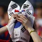 Seorang warga menutupi wajahnya dengan bendera Korea Selatan usai timnasnya dikalahkan Belgia 0-1, Seoul, Jumat (27/6/14). (REUTERS/Kim Hong-Ji)