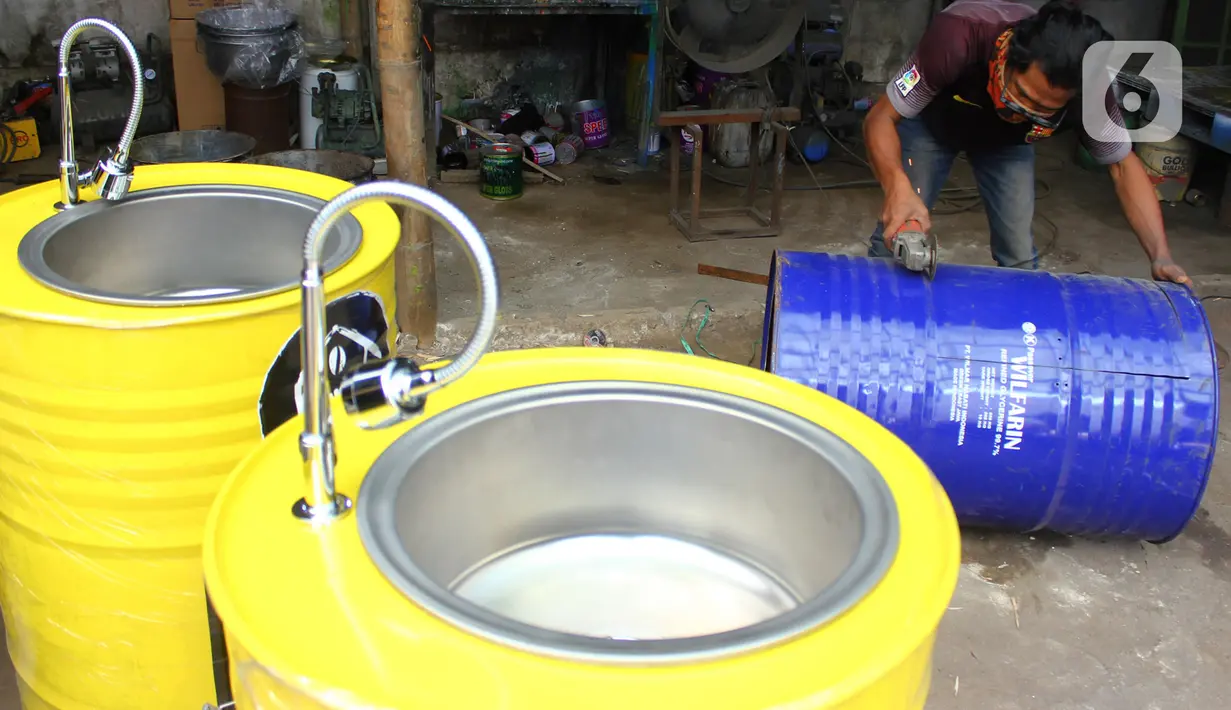 Perajin memproduksi wastafel portabel berbahan baku drum di workshop Galuh Creatives, Tangerang Selatan, Sabtu (30/5/2020). Wacana pemerintah menerapkan tatanan normal baru berimbas pada meningkatnya pesanan wastafel portabel yang dijual seharga Rp1,2 juta per unit. (merdeka.com/Arie Basuki)