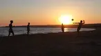 Sejumlah orang bermain bola saat matahari terbenam di pantai Sampieri, Sisilia, (31/7). (AFP Photo/Ludovic Marin)
