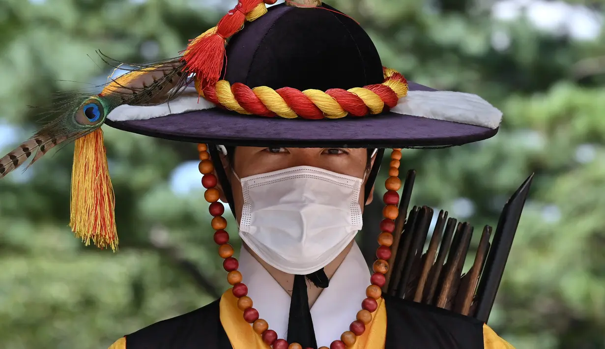 Anggota 'penjaga istana' yang mengenakan masker berdiri untuk turis di gerbang utama Istana Deoksugung di Seoul (4/9/2020). Korea Selatan melaporkan 198 kasus Covid-19 baru pada 4 September, hari ke-22 berturut-turut meningkat tiga digit. (AFP/Jung Yeon-je)