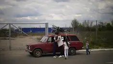 Orlyanske (kiri) memeluk istrinya Kolya di samping mobil mereka saat mereka tiba dari Vasylivka ke pusat penerimaan pengungsi di Zaporizhzhia, Ukraina, Selasa (3/5/2022). Ribuan warga Ukraina terus meninggalkan wilayah yang diduduki Rusia. (AP Photo/Francisco Seco)