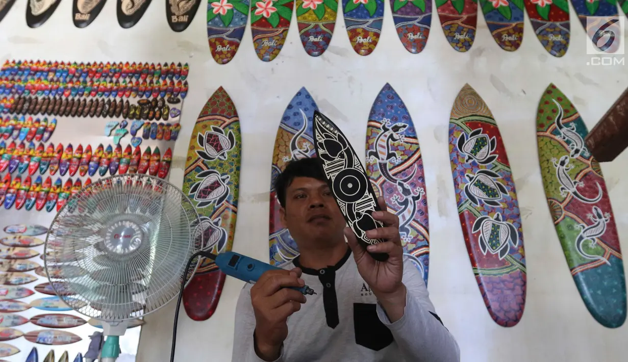 Pengrajin tengah membuat sovenir papan seluncur di Bali, Senin (15/10). Sektor pariwisata menjadi salah satu penyumbang cepat datangnya devisa. (Liputan6.com/Angga Yuniar)