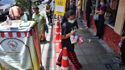 Orang-orang berbaris untuk mengumpulkan barang-barang yang disumbangkan oleh publik pada “Pantry of Sharing” di Bangkok, Rabu (13/5/2020). Warga yang mampu menaruh kelebihan stok makanannya di lemari itu, sementara yang tidak mampu mengambil persediaan sesuai kebutuhan. (Lillian SUWANRUMPHA/AFP)