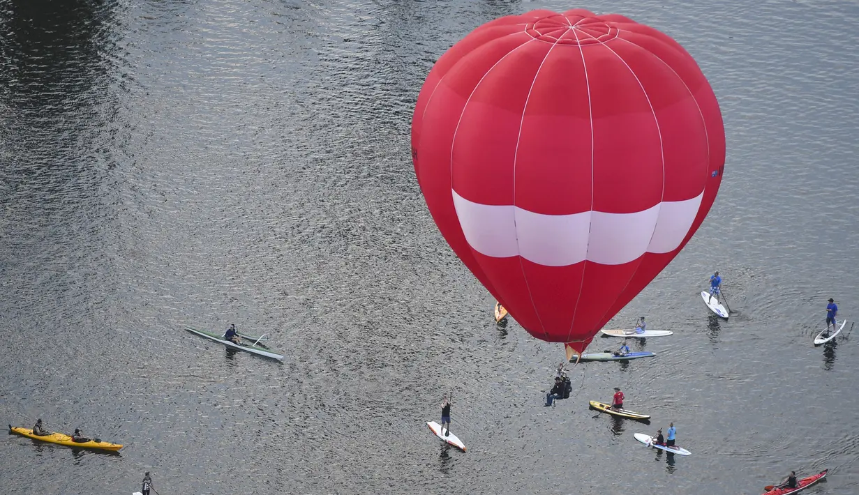 Para pedayung saat melihat balon udara yang terbang diatas danau Burley Griffin, Canberra,  Australia, (15/3). Ini dilakukan dilakukan dalam memperingati ulang tahun ke-30 festival Balloon Spectacular Canberra . (REUTERS / Lukas Coch)