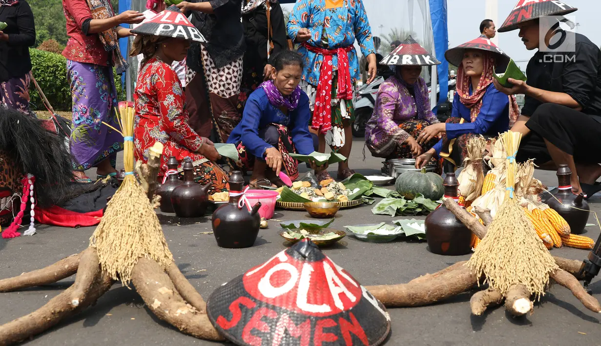 Sejumlah petani Kendeng membagi makanan saat aksi di depan Istana Negara, Jakarta, Kamis (2/8). Dalam aksinya, petani Kendeng melakukan tradisi Brokohan atau makan bersama nasi aneka urap yang sebelumnya didoakan. (Liputan6.com/Helmi Fithriansyah)
