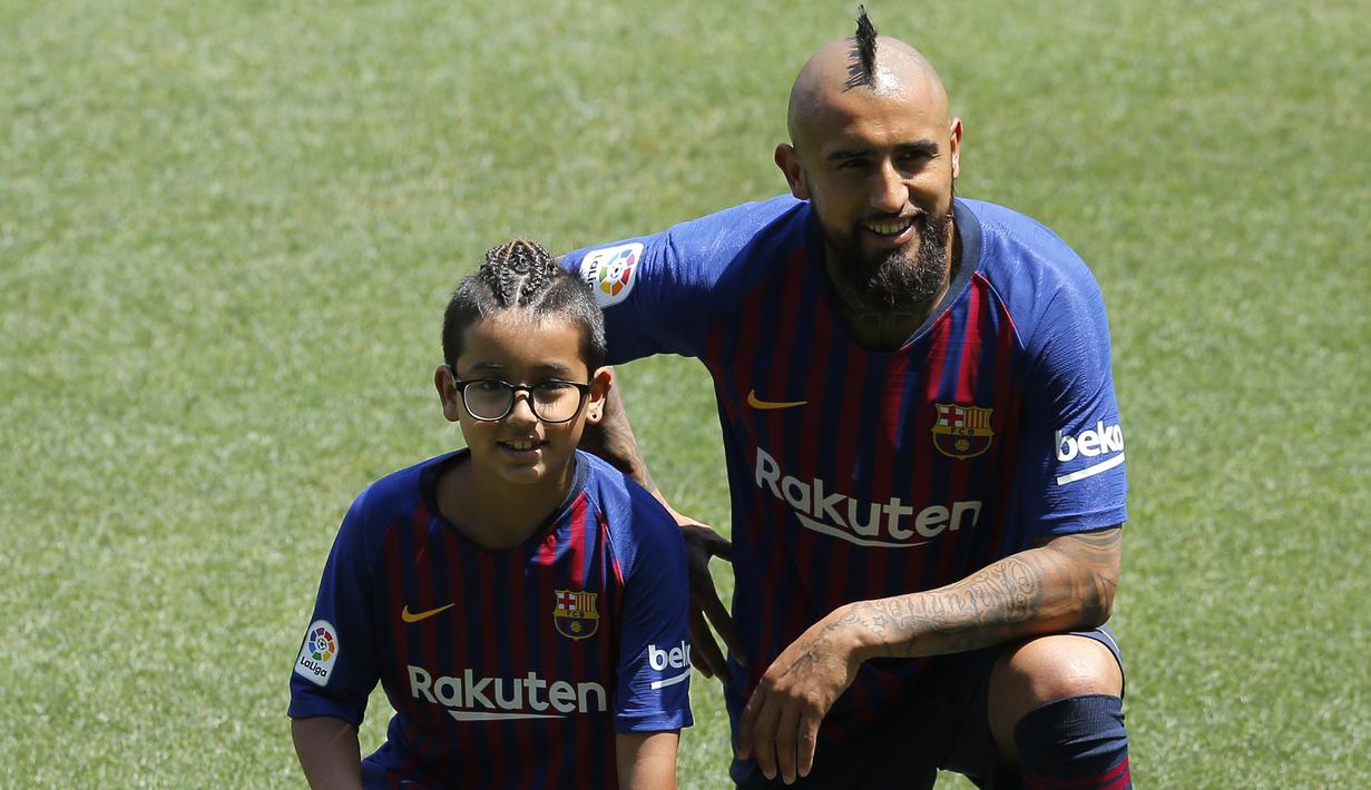 Pemain baru Barcelona, Arturo Vidal, bersama anaknya Alonso, saat perkenalan di Stadion Camp Nou, Senin, (7/8/2018). Barcelona merogoh kocek sebesar 19 juta euro untuk mengamankan jasa pria berkebangsaan Cile itu. (AP/Manu Fernandez)