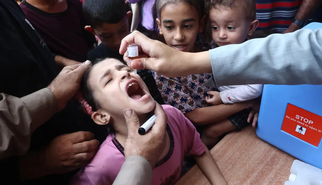 Anak-anak Palestina menerima tetesan vaksin sebagai bagian dari program vaksinasi polio di Deir al-Balah di Jalur Gaza tengah pada 14 Oktober 2024. (Eyad BABA/AFP)