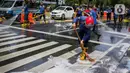 Sejumlah personil pemadam kebakaran membersihkan tumpah oli yang terjadi di Jalan Veteran depan Gedung Krida Bakti, Jakarta, Kamis (16/1/2020). Petugas damkar  melakukan pembersihan dengan cairan deterjen maupun campuran khusus agar jalan tersebut tidak lagi licin. (Liputan6.com/Faizal Fanani)