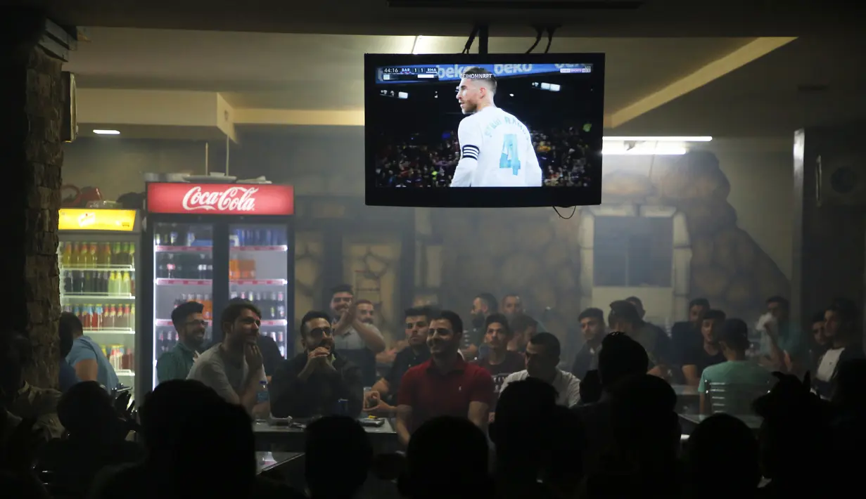 Warga Palestina menyaksikan pertandingan sepak bola El Clasico antara Real Madrid dan Barcelona FC di sebuah kafe di kota Ramallah, Tepi Barat (6/5). Real Madrid dan Barcelona meraih hasil imbang 2-2 di pertandingan tersebut. (AFP Photo/Abbas Momani)