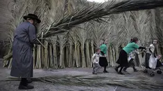 Anak-anak bermain di dekat seorang pria Yahudi Ultra-Ortodoks yang membawa daun pohon palem di Yerusalem (1/10). Hari Raya Sukkot merupakan salah satu hari raya besar umat Yahudi yang dalam bahasa Ibrani disebut Tabernakel. (AFP Photo/Manahem Kahana)