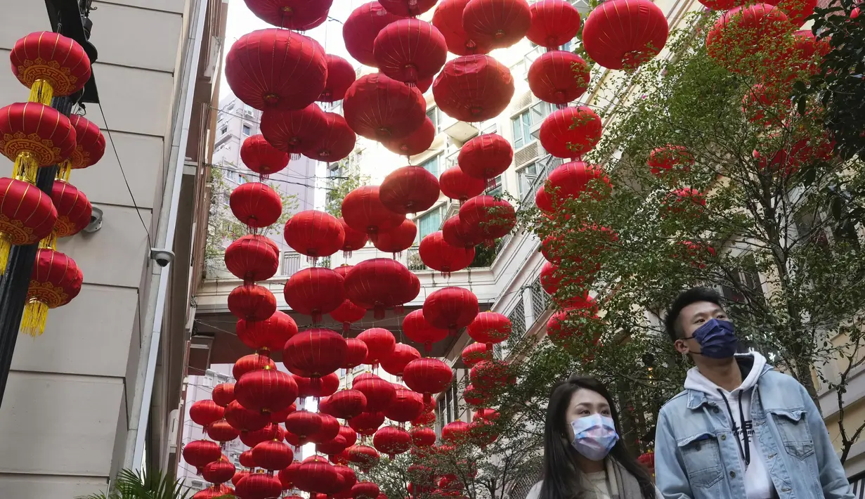 Orang-orang berjalan melewati dekorasi untuk merayakan Tahun Baru Imlek di Hong Kong, Minggu (30/1/2022). Tahun Baru China atau Imlek jatuh pada 1 Februari (AP Photo/Vincent Yu)