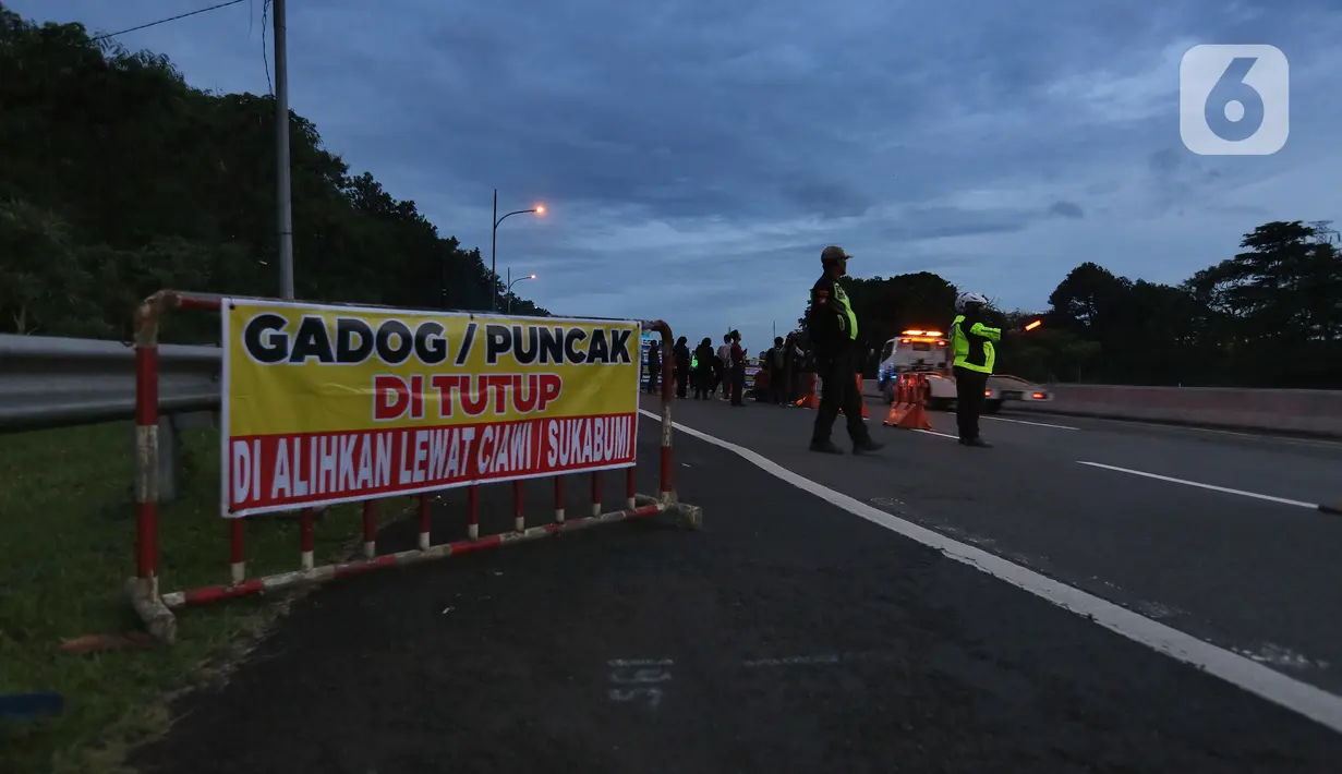 Petugas dari Polres Bogor memasang rambu penutupan jalan di pintu keluar Tol Gadog, Bogor, Sabtu (31/12/2022). Penutupan jalan jalur Puncak Bogor untuk gelaran Car Free Night dimulai sejak pukul 18.00 WIBdan dibuka kembali esok pagi pukul 06.00 WIB. (merdeka.com/Arie Basuki)